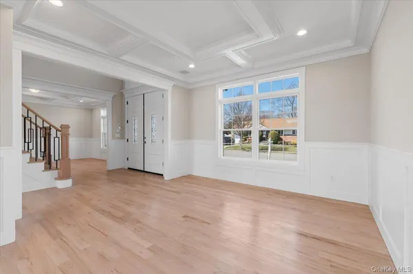 a view of an empty room with wooden floor and a kitchen