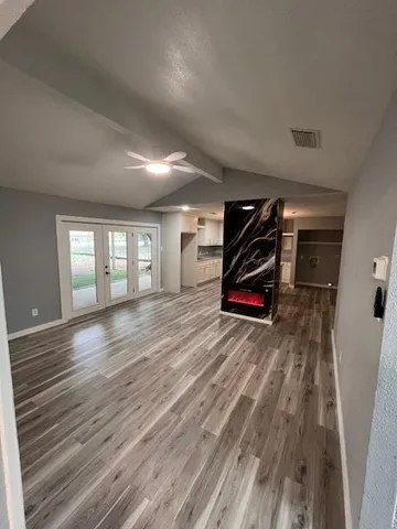 a view of an empty room with wooden floor and window