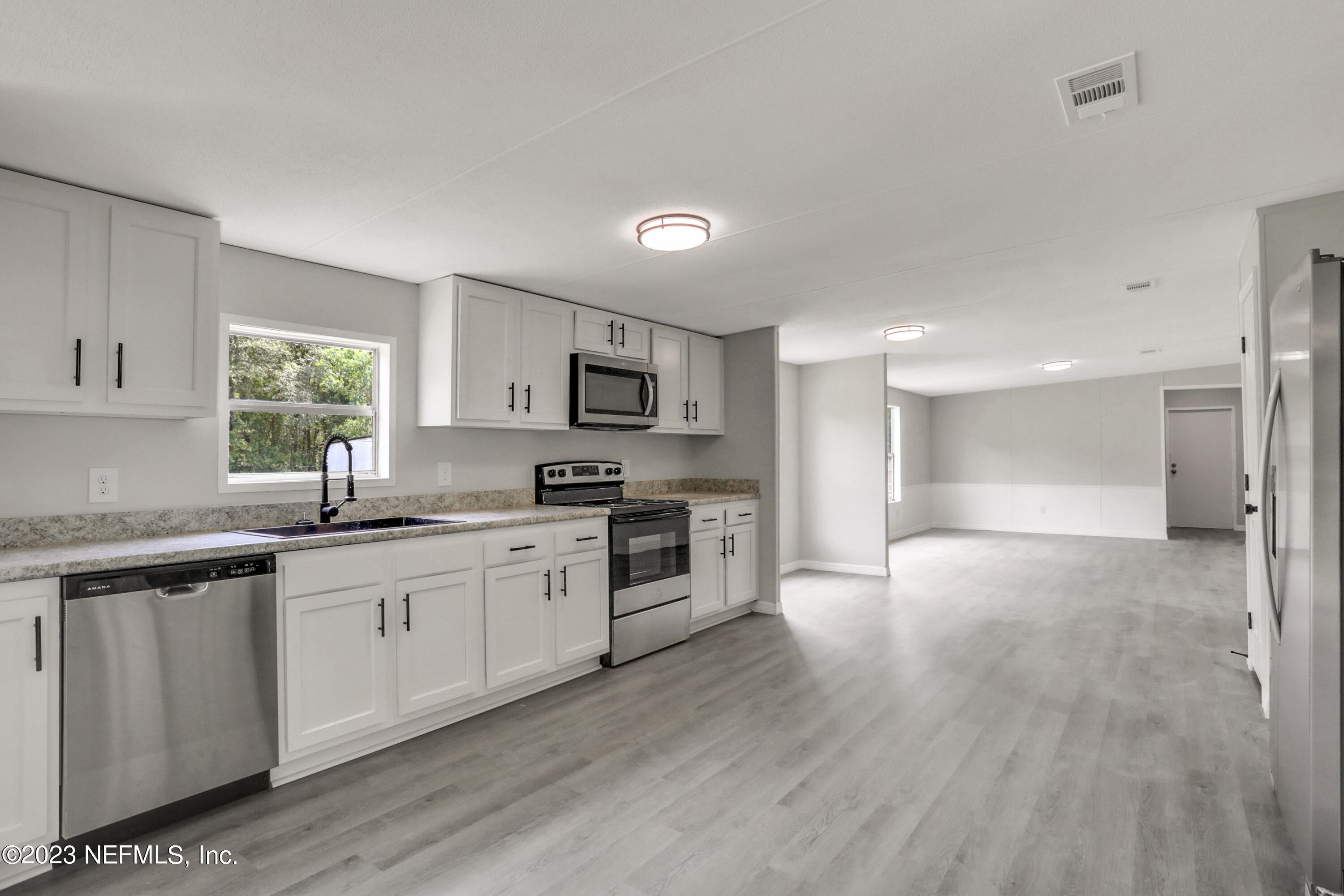 10765 Boddens Road Jacksonville, FL 32219 - Photo 20 of 39 a large kitchen with cabinets wooden floor and stainless steel appliances