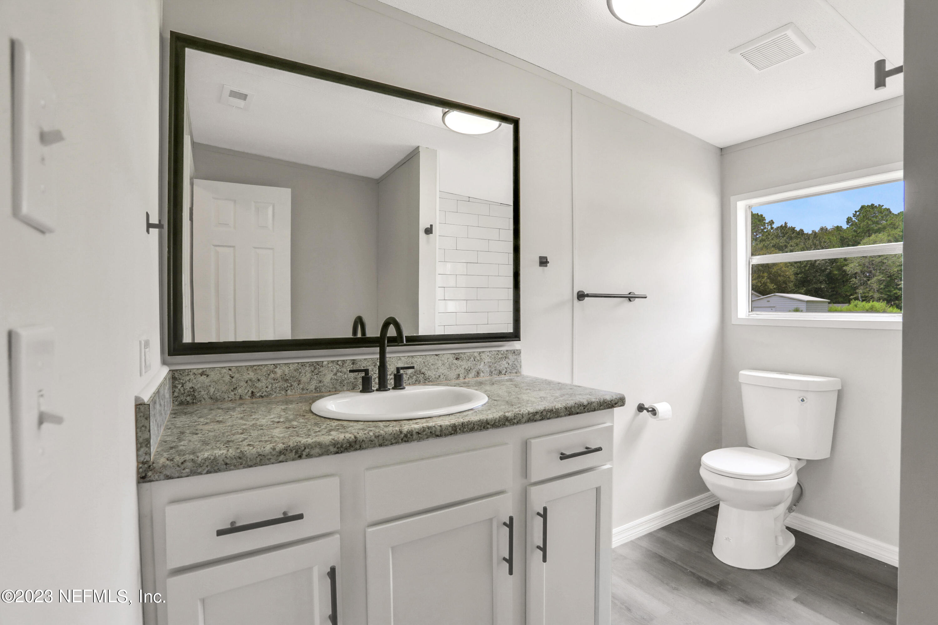 10765 Boddens Road Jacksonville, FL 32219 - Photo 10 of 39 a bathroom with a granite countertop toilet sink and mirror