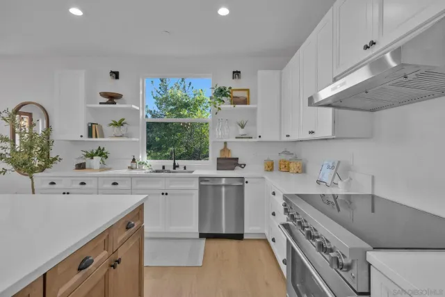 a kitchen with stainless steel appliances kitchen island granite countertop a table chairs and a refrigerator