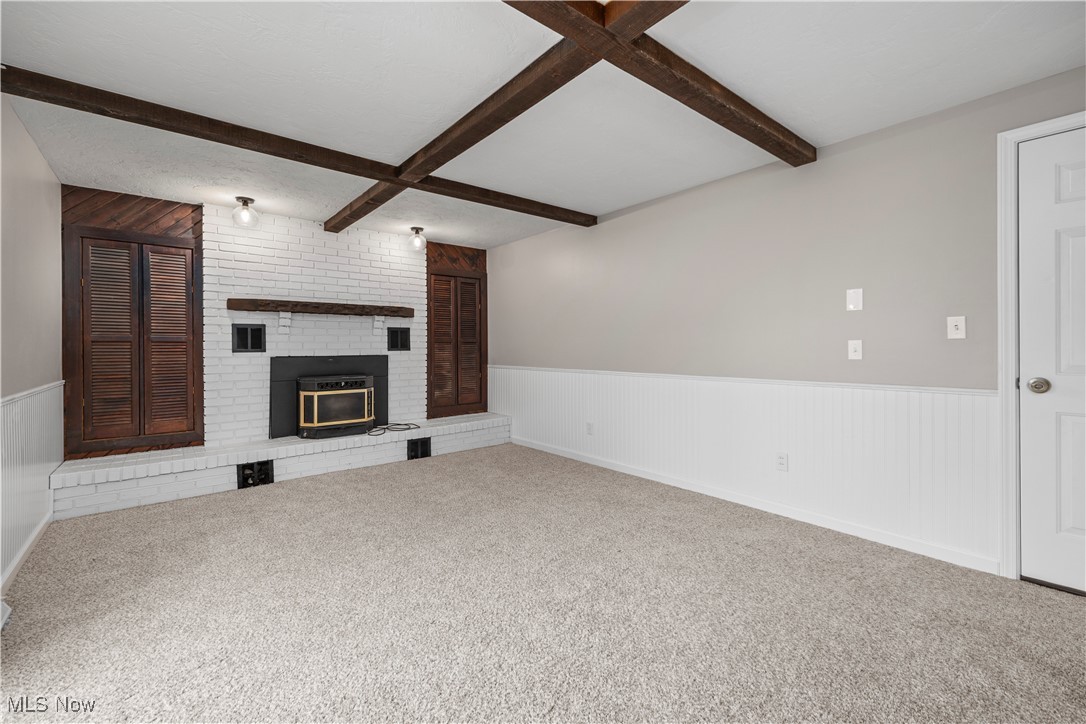 6265 Jaycox Road North Ridgeville, OH 44039 - Photo 16 of 39 Unfurnished living room featuring beamed ceiling, wainscoting, carpet flooring, and a brick fireplace