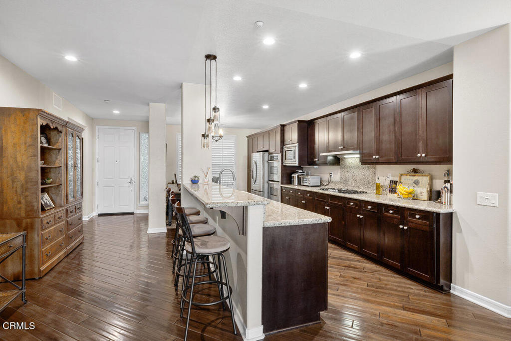 1544 Seabridge Lane Oxnard, CA 93035 - Photo 12 of 30 a large kitchen with stainless steel appliances kitchen island granite countertop a refrigerator a stove a sink a dining table and chairs with wooden floor