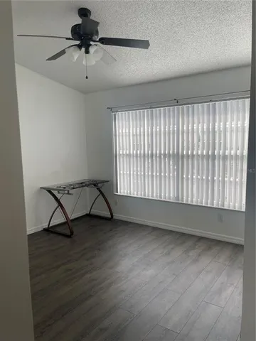 an empty room with wooden floor chandelier fan and windows