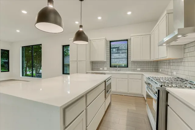 a large white kitchen with a large window a sink stainless steel appliances and a counter space