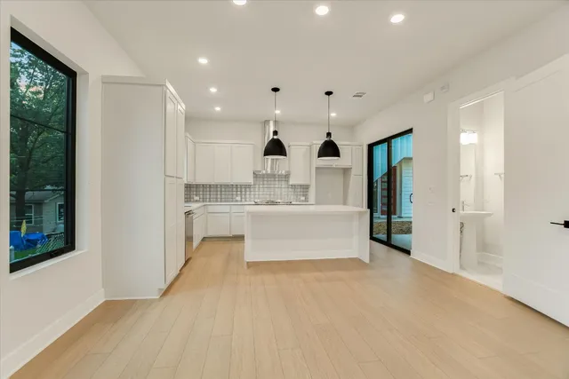 a large white kitchen with kitchen island a sink stainless steel appliances and cabinets