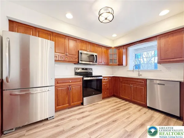 a kitchen with granite countertop stainless steel appliances a refrigerator cabinets and wooden floor