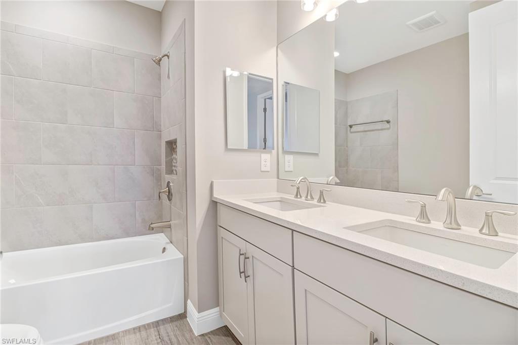 4652 Centaurus Circle Naples, FL 34120 - Photo 24 of 45 Bathroom with double vanity, bathtub / shower combination, and light wood-style flooring