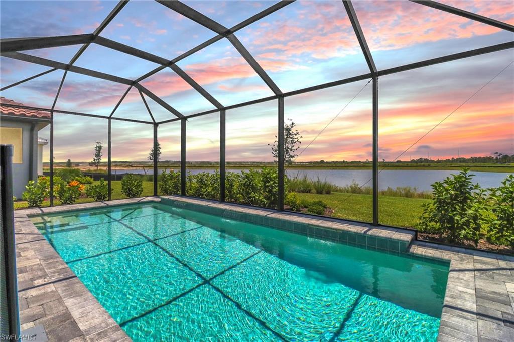 4652 Centaurus Circle Naples, FL 34120 - Photo 29 of 45 Pool at dusk featuring an outdoor pool, a sunroom, and glass enclosure