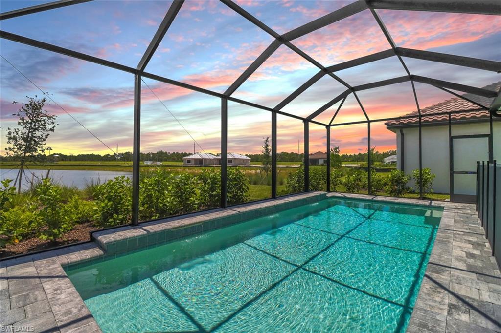 4652 Centaurus Circle Naples, FL 34120 - Photo 31 of 45 Pool at dusk featuring an outdoor pool, a sunroom, and a lanai