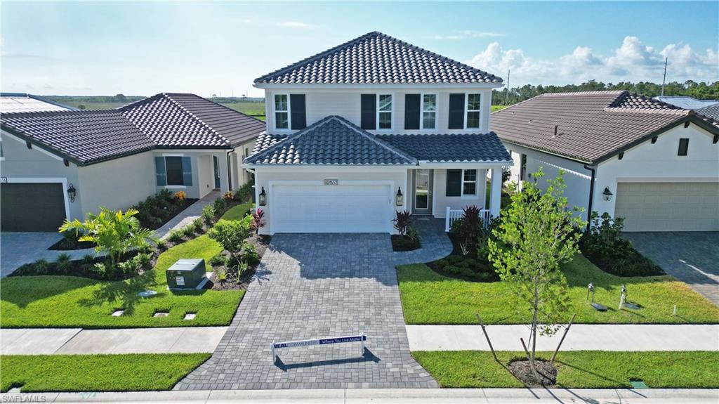 4652 Centaurus Circle Naples, FL 34120 - Photo 43 of 45 View of front of property featuring a tiled roof, an attached garage, decorative driveway, a porch, and a front lawn