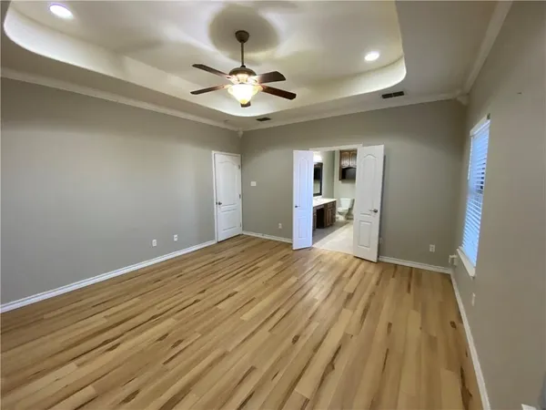 a view of an empty room and chandelier fan and kitchen view