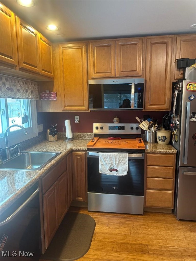 112 Stratford Road Painesville, OH 44077 - Photo 6 of 12 Kitchen featuring stainless steel appliances, brown cabinetry, and light wood-style floors