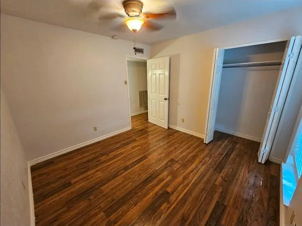 an empty room with wooden floor fan and window