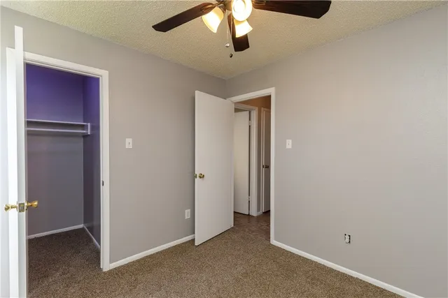 an empty room with closet and a chandelier fan