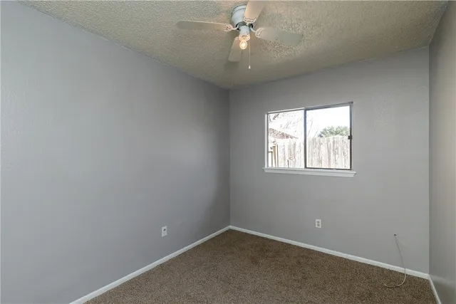 an empty room with a window and ceiling fan