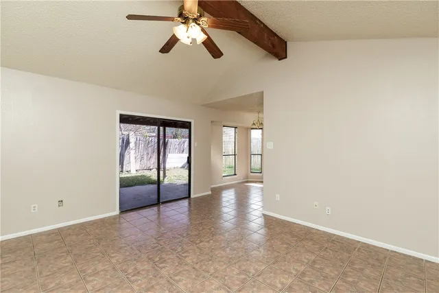 an empty room with chandelier fan and windows