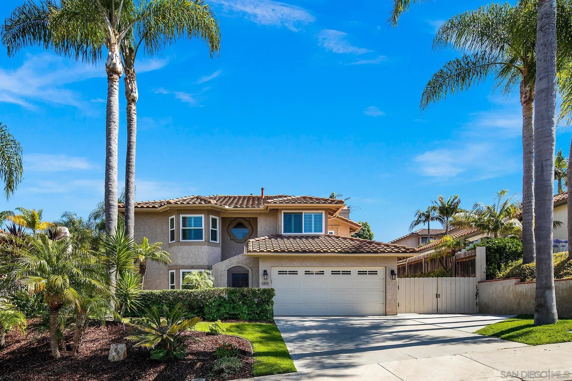 a view of a house with a yard and palm trees