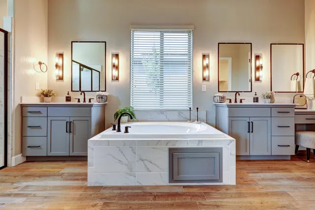 a spacious bathroom with a granite countertop sink a mirror a vanity and a bathtub