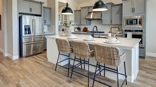 a kitchen with stainless steel appliances granite countertop a kitchen island hardwood floor and a sink