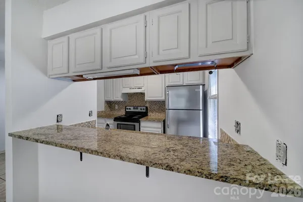 a kitchen with granite countertop a sink a stove and cabinets