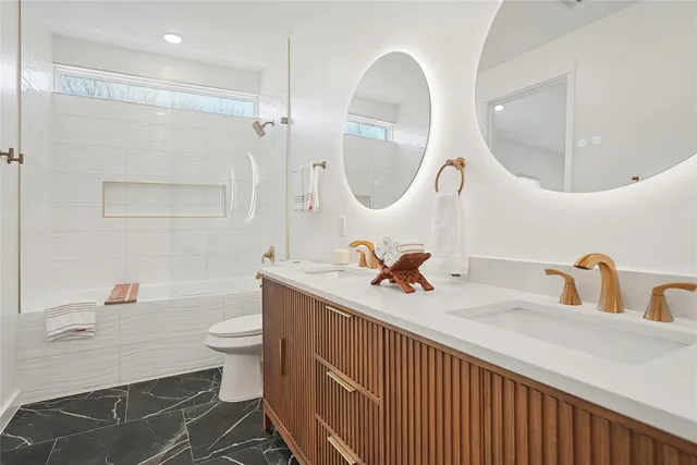 a bathroom with a double vanity sink mirror and toilet