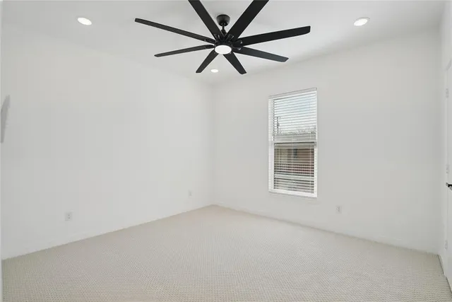 an empty room with a window and a ceiling fan
