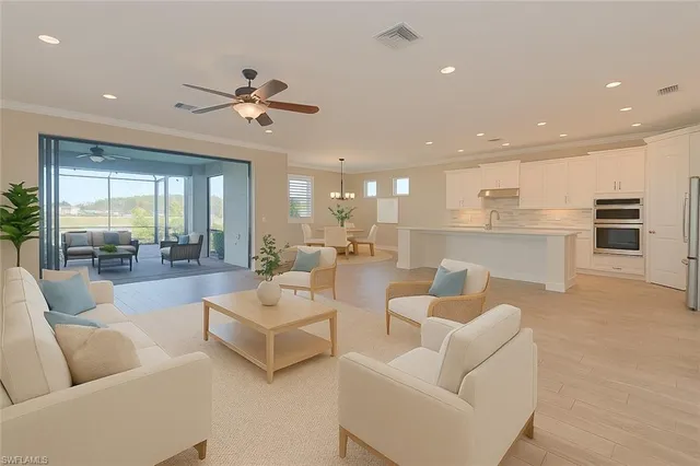 a living room with furniture kitchen view and a large window