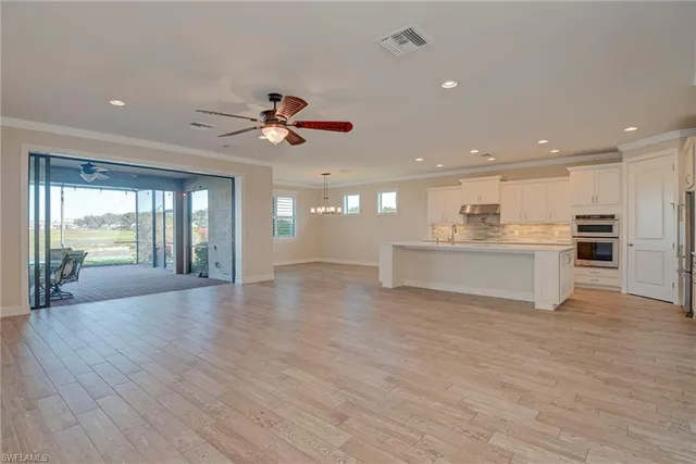 a view of a big room with wooden floor and a kitchen