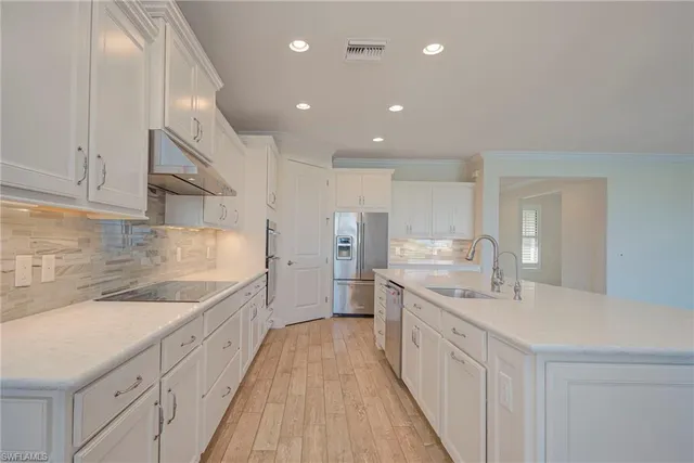 a large kitchen with stainless steel appliances kitchen island a large counter top and a sink