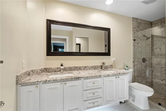 a bathroom with a granite countertop toilet sink and mirror