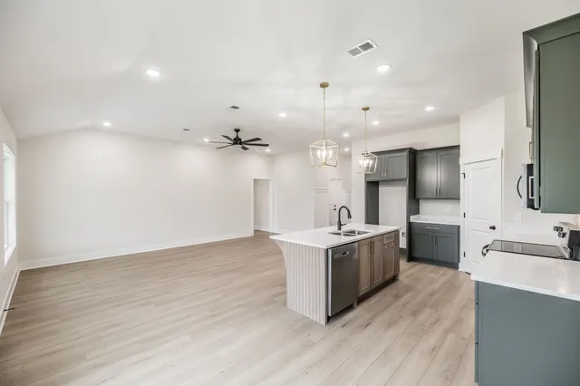 a large kitchen with a large counter top a sink stainless steel appliances and cabinets
