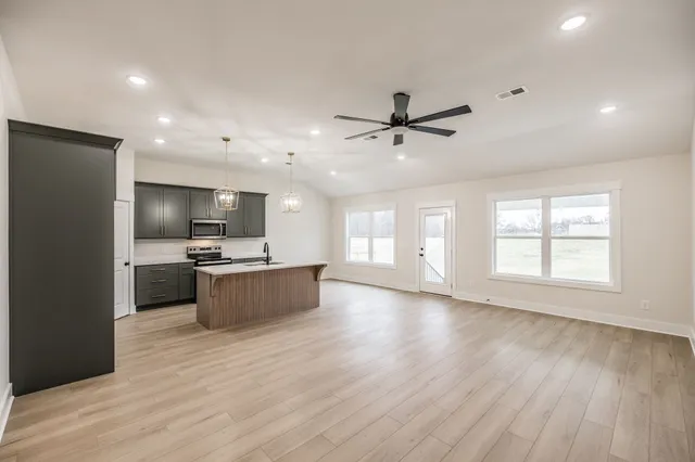 a large kitchen with stainless steel appliances a large counter top a sink a refrigerator and a window