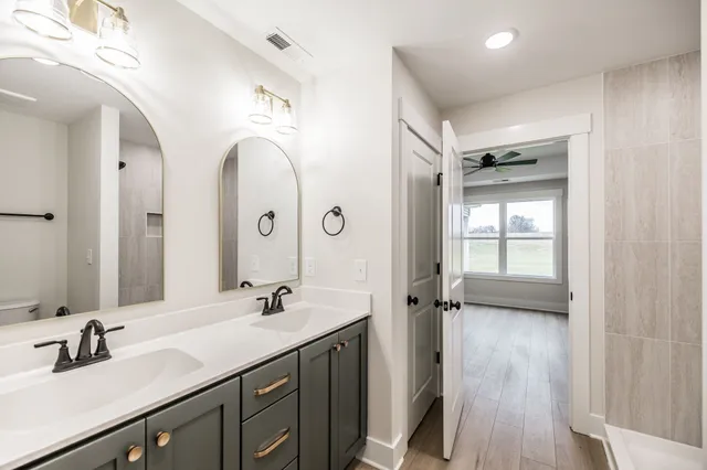 a en suite bathroom with a double vanity sink a mirror and a shower