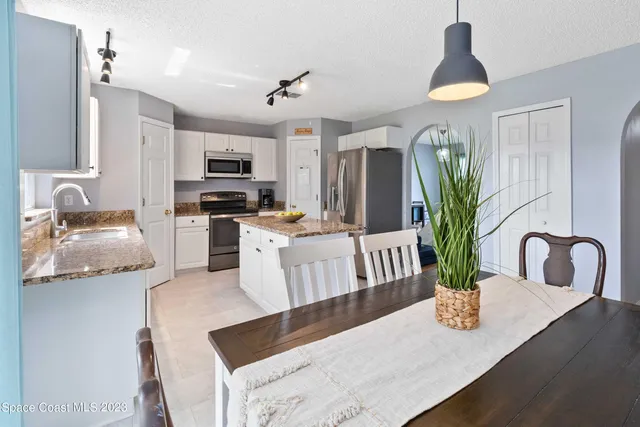 a kitchen with stainless steel appliances granite countertop a table chairs and a refrigerator