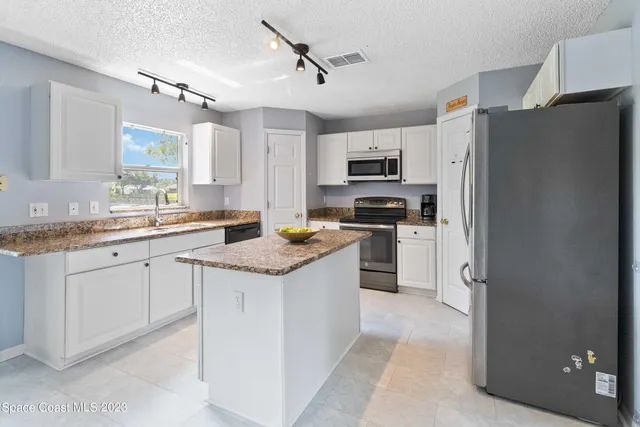a kitchen with kitchen island granite countertop appliances cabinets and a sink