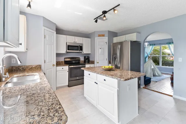 a kitchen with granite countertop a stove top oven a sink dishwasher a dining table and chairs with wooden floor