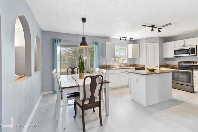 a dining room kitchen with stainless steel appliances granite countertop a stove a sink dishwasher a dining table and chairs with wooden floor