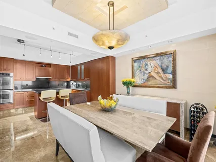 a kitchen with stainless steel appliances granite countertop a stove a sink a dining table and chairs with wooden floor