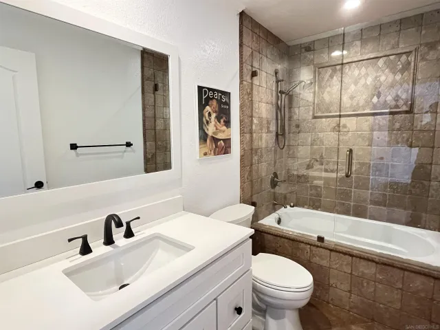 a living room with a black white checkered floor with a gaming machine and dining chairs