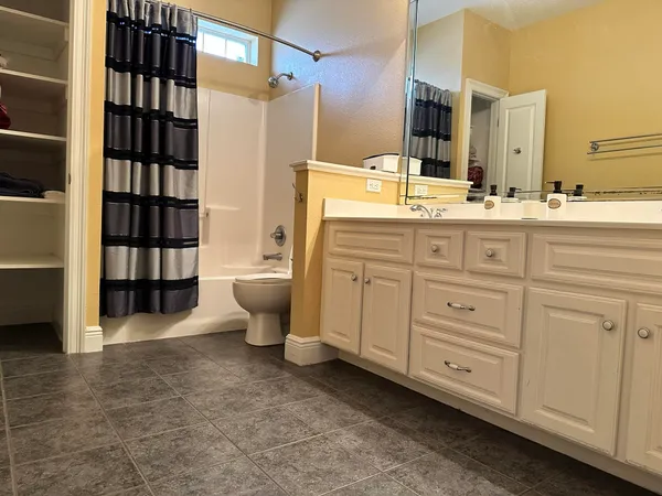 a bathroom with a double vanity sink a toilet and shower
