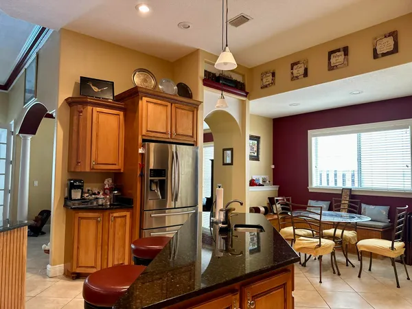 a kitchen with stainless steel appliances granite countertop a refrigerator a sink dishwasher a dining table and chairs with wooden floor