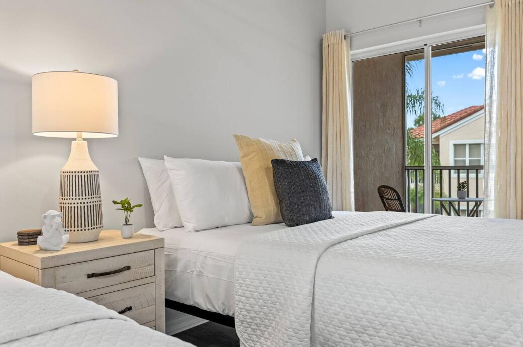 9969 Perfect Drive, Unit B Port St. Lucie, FL 34986 - Photo 6 of 8 a bedroom with a bed and a lamp on table