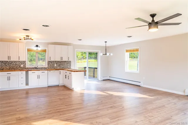 a large kitchen with stainless steel appliances granite countertop a stove a sink and white cabinets with wooden floor