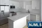 a kitchen with stainless steel appliances a sink a stove a microwave a refrigerator a counter space and cabinets