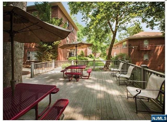 280-320 Oak Street, Unit 314 TI Ridgewood, NJ 07450 - Photo 7 of 15 a view of a roof deck with table and chairs under an umbrella with a small yard