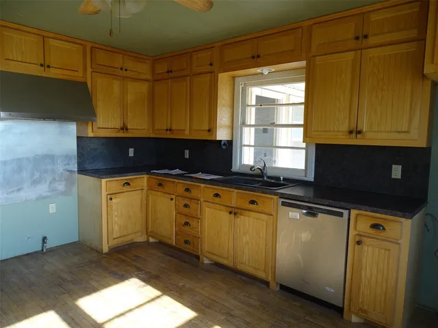 a kitchen with granite countertop cabinets stainless steel appliances a sink and wooden floor