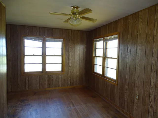 a view of an empty room with a window and wooden floor