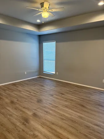 a view of an empty room with wooden floor and chandelier