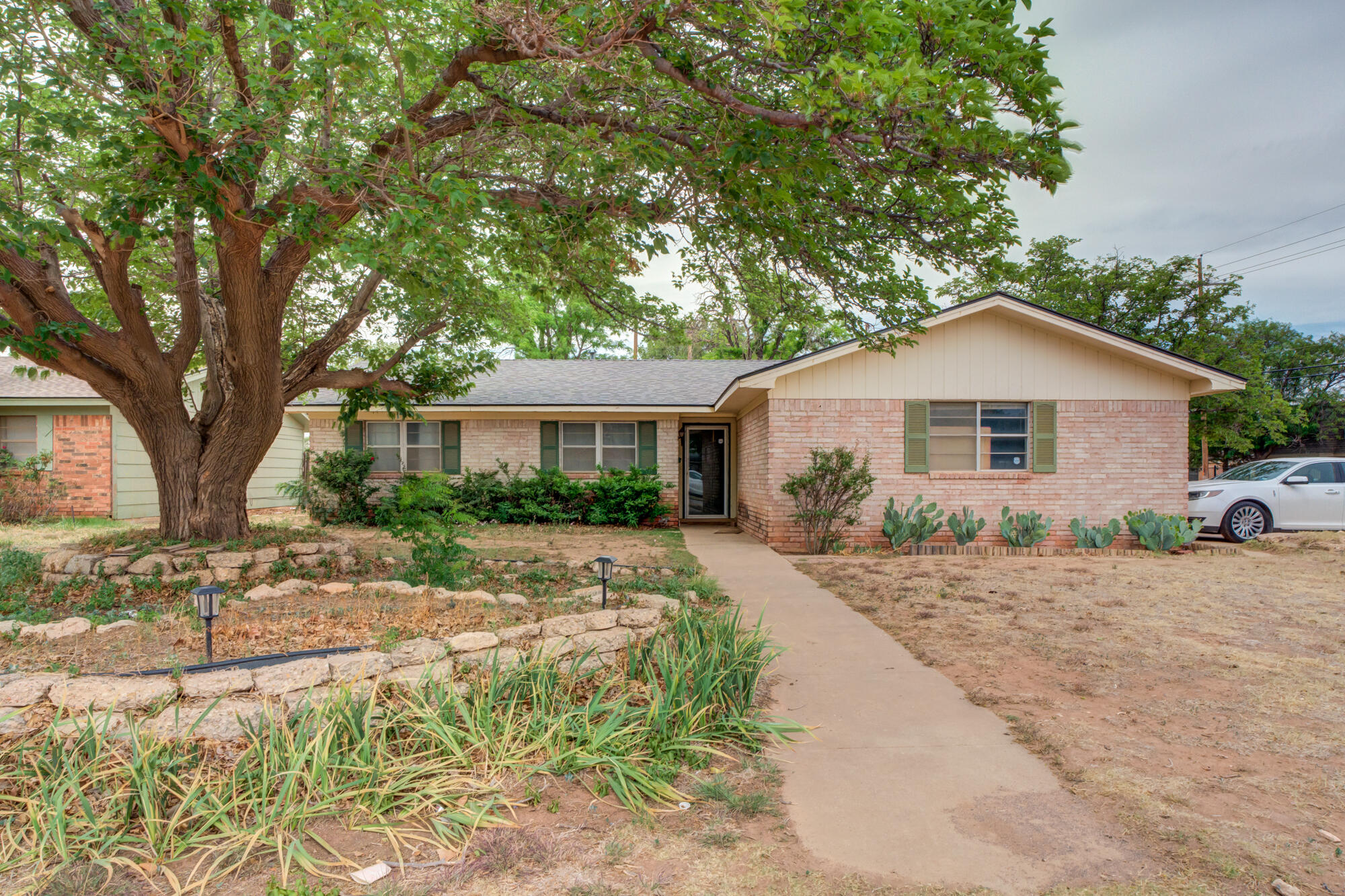 4802 53rd Street Lubbock, TX 79414 - Photo 1 of 31 a front view of a house with a dirt yard and a large tree